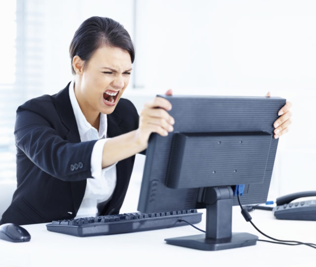 Portrait of a young business woman holding computer monitor in anger